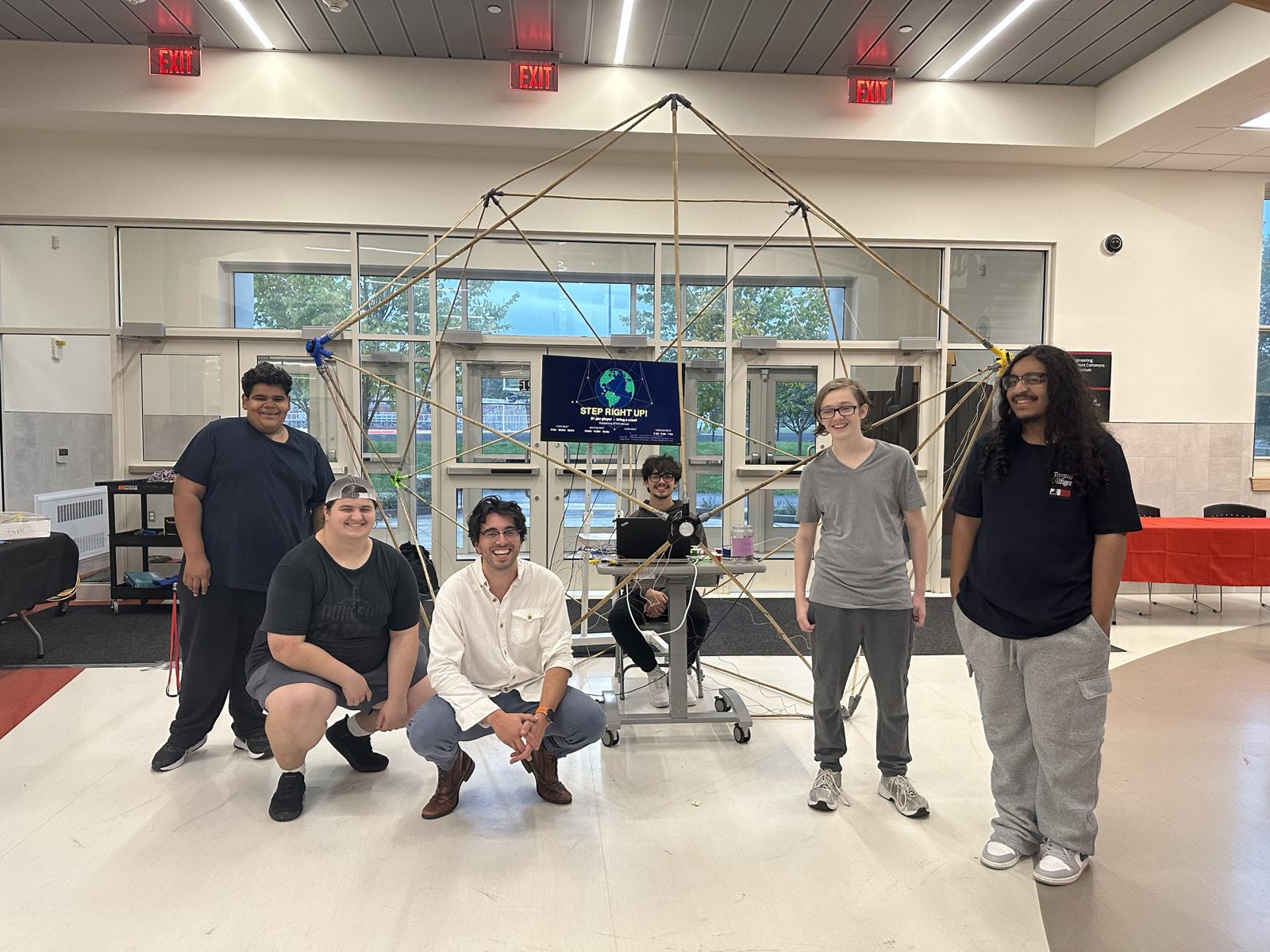 Students and a teacher posing in front of the finished GeoGlobe sculpture at the open house